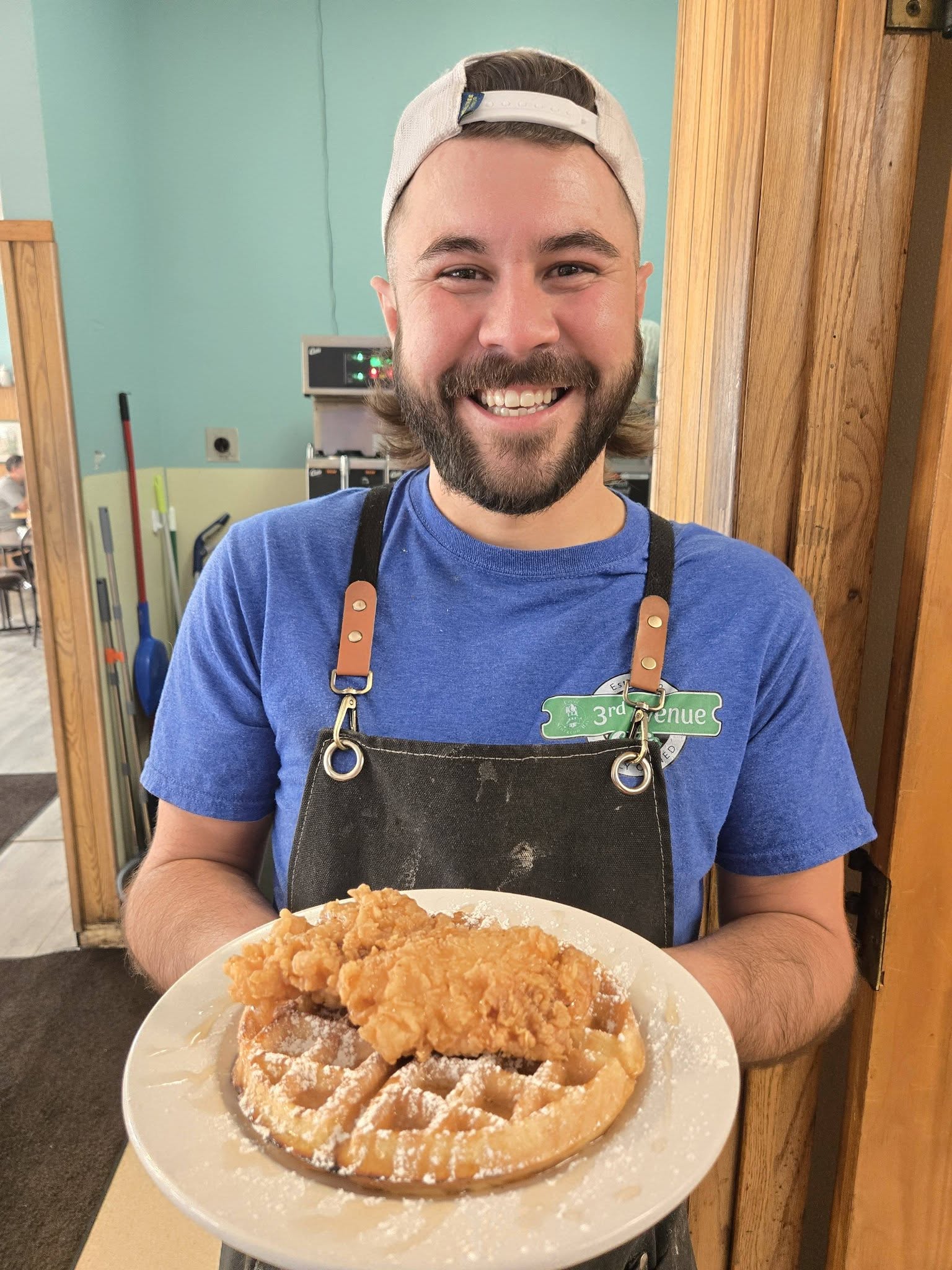 3rd Avenue Cafe staff member holding chicken and waffles